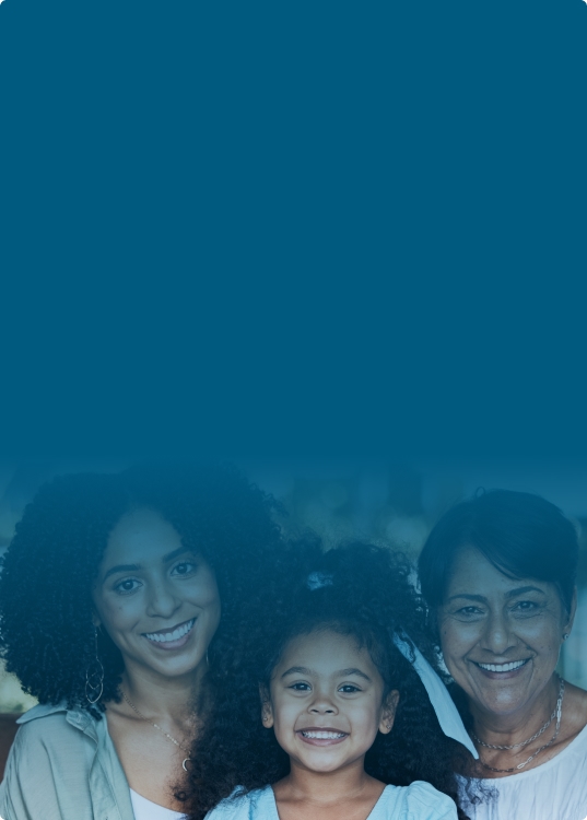 CUna familia compuesta por dos mujeres y un niño, sonriendo juntas en un entorno acogedor.